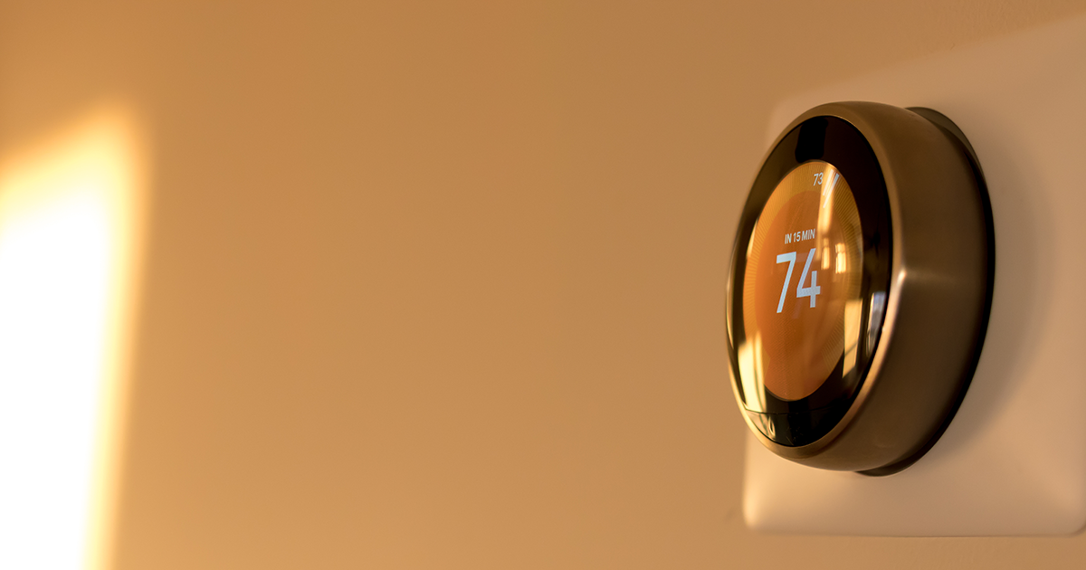 Hand adjusting a heat pump thermostat on the wall