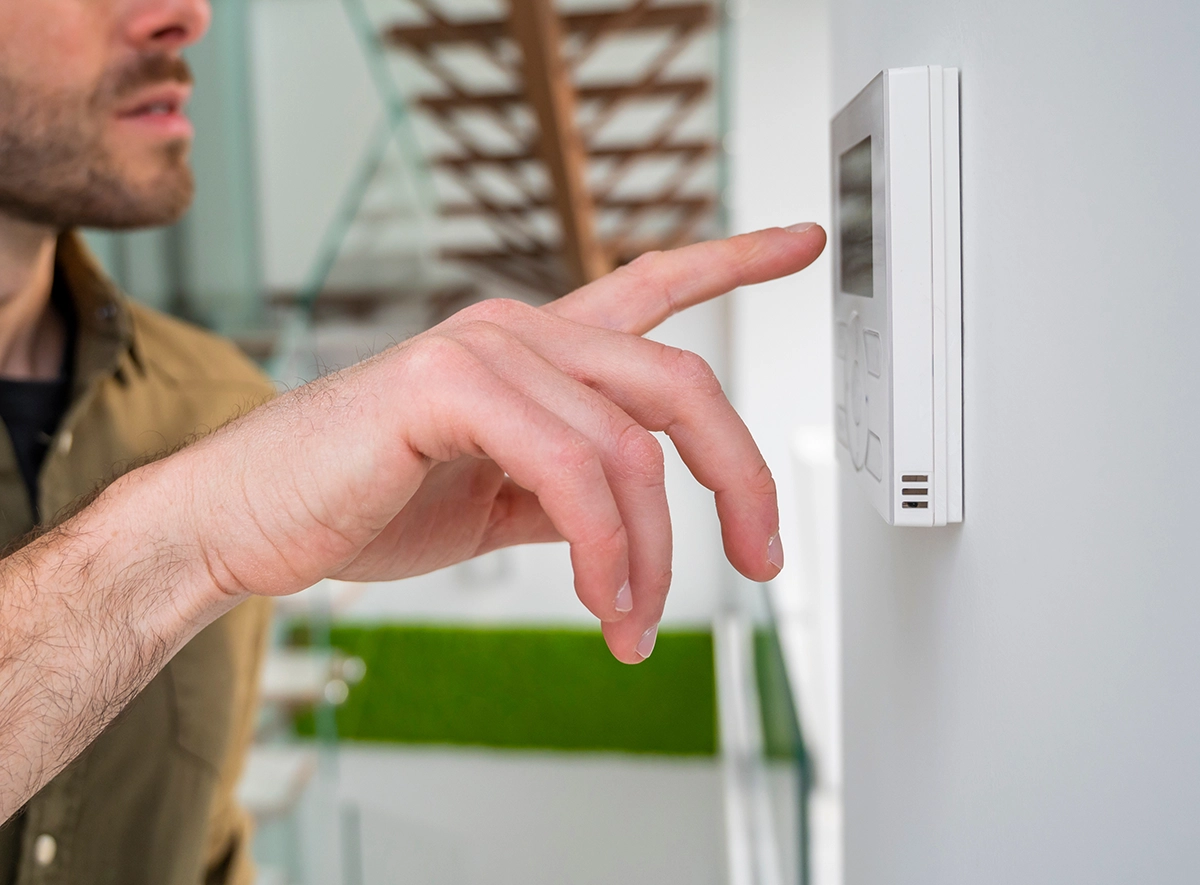 Homeowner adjusting a thermostat when AUX heat is in use on a heat pump system