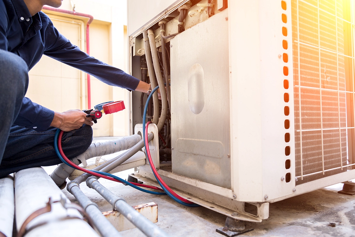 Technician checking AC refrigerant levels on an outdoor air conditioning unit during professional service