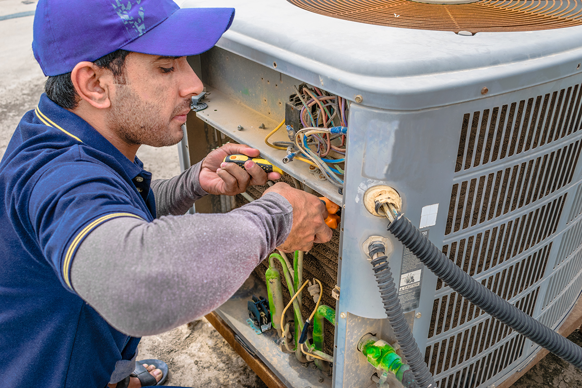 HVAC technician inspecting wiring on an outdoor unit during AC repair in North Las Vegas.